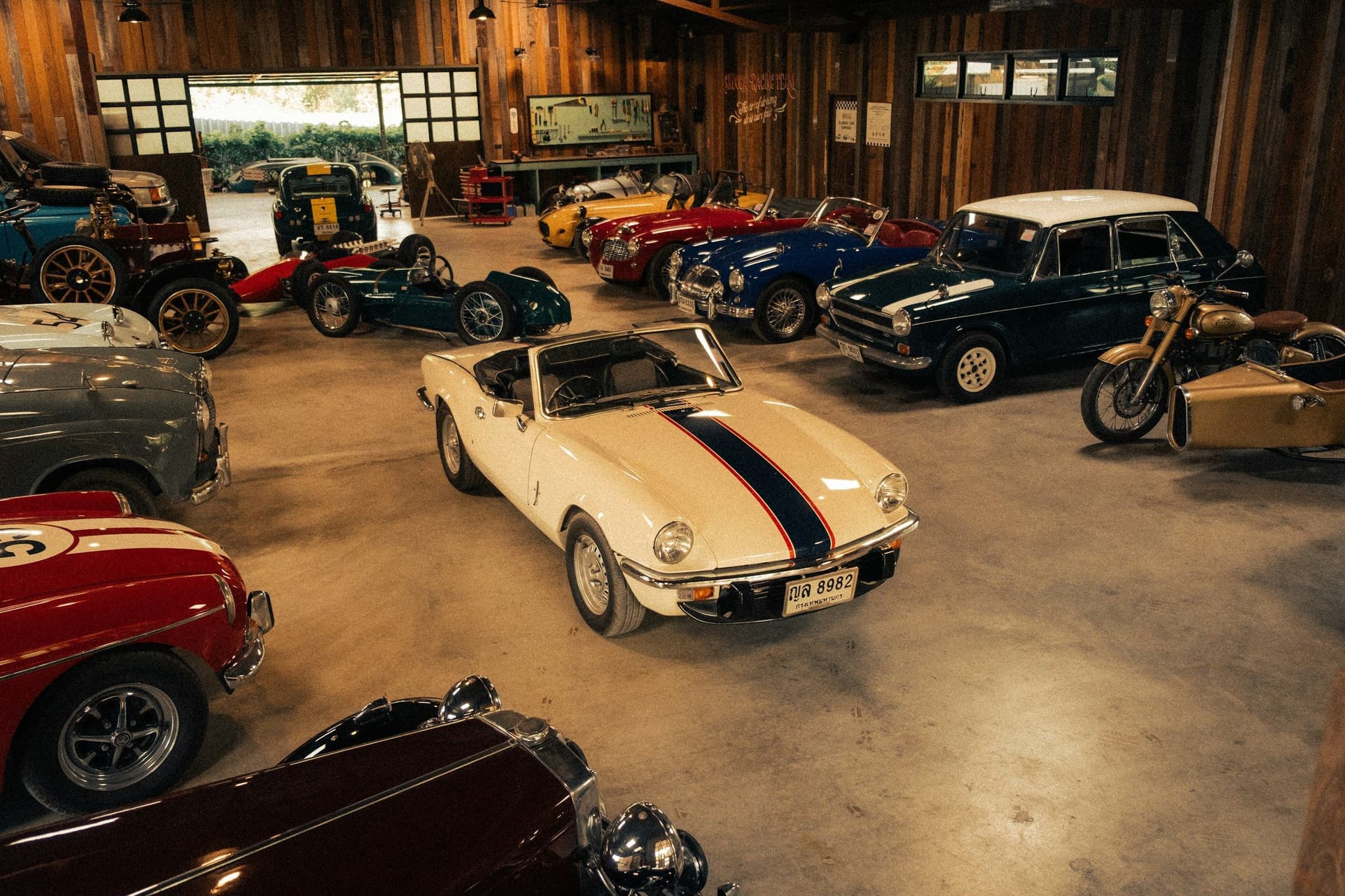 Classic cars and a vintage motorcycle arranged on a polished garage floor